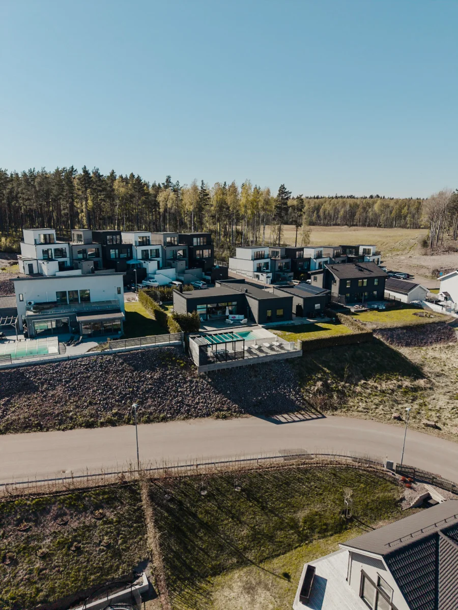 Drönarbild över ett område med moderna radhus i kvällssol